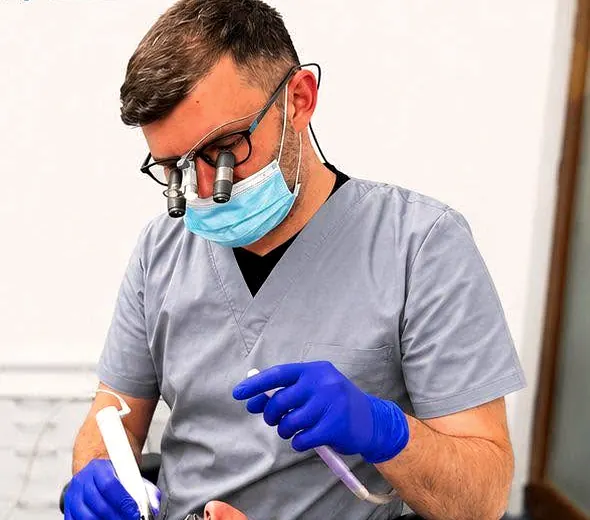 Dr. Andrei Anuțoiu, cu lupe de mărire și mănuși, în timpul unui tratament de canal